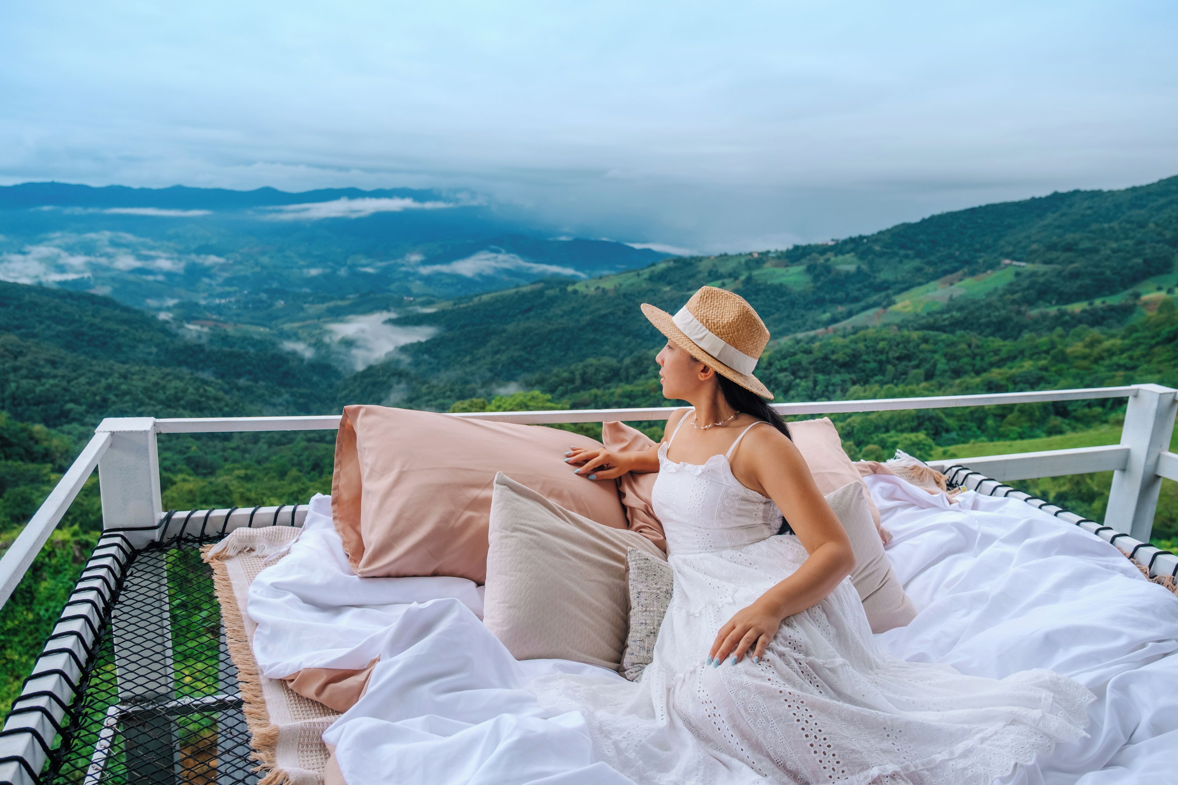 A person sitting on a bed with a view of a mountainous landscape.
