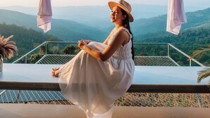 Une femme est assise sur un balcon, d’où l’on peut admirer la vue sur les montagnes.