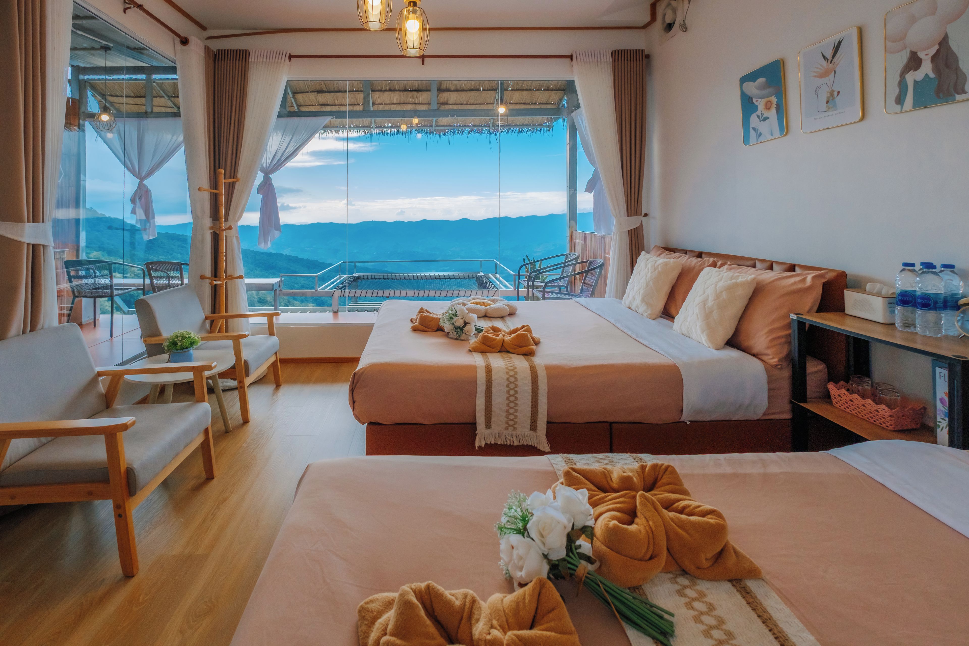 A hotel room with two beds, a balcony with a view of the mountains, and a dining area with a table and chairs.