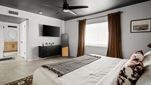 A bedroom with a bed, a ceiling fan, a TV, a window with curtains, a bedside table, and a wall-mounted TV. - Sport Court | Private Heated Pool | Mini Golf & More (Glendale)