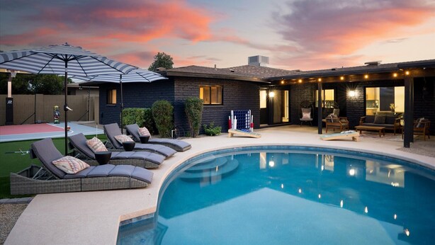 A swimming pool with lounge chairs, a covered patio, and a house with a brick exterior. - Sport Court | Private Heated Pool | Mini Golf & More (Glendale)