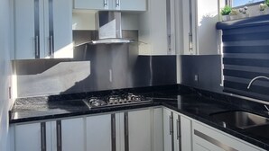 Een moderne keuken met witte kasten, een zwart aanrechtblad en een roestvrijstalen afzuigkap.