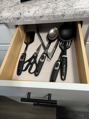 Un cajón con utensilios de cocina, como espátula, pinzas y cuchara.