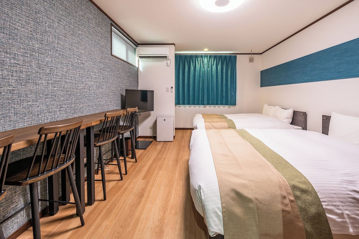 Ein Hotelzimmer mit Schreibtisch, Stühlen, einem Bett und einem Fernseher.