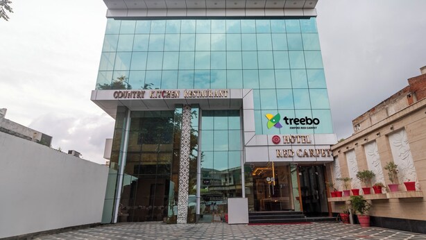 A modern building with a glass facade, a sign for 'Country Kitchen Restaurant', and a 'Treebo Empire Red Carpet' logo. - Treebo Empire Red Carpet (Agra)
