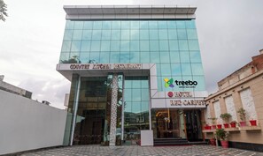 A modern building with a glass facade, a sign for 'Country Kitchen Restaurant', and a 'Treebo Empire Red Carpet' logo.