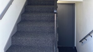 A staircase with carpeted steps leading to a dark door with a brass doorknob.