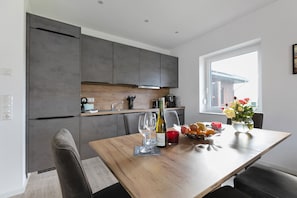 Una cocina moderna con armarios grises, una mesa de comedor de madera y una ventana con vistas.