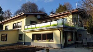 Una casa de dues plantes amb un balcó, una antena parabòlica i un petit jardí.