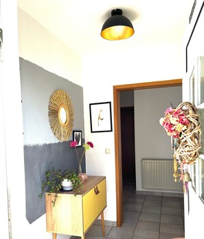 A hallway with a wooden console table, a wall-mounted mirror, a framed picture, and a decorative wreath. - Apartment 'Lichte Wohnung Zum Wohlfühlen' with Balcony and Wi-Fi (Bastheim)