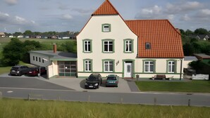 Ein zweistöckiges Haus mit rotem Dach, grünen Fensterrahmen und einer Garage.