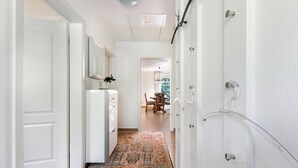 Un pasillo con un tapete estampado, un refrigerador y una puerta que da a otra habitación.