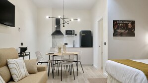 A compact hotel room with a kitchenette, a dining area with a table and chairs, a sofa, and a bed. - Romantic Apartment N5 Oceanografico Virkin Suites (València)