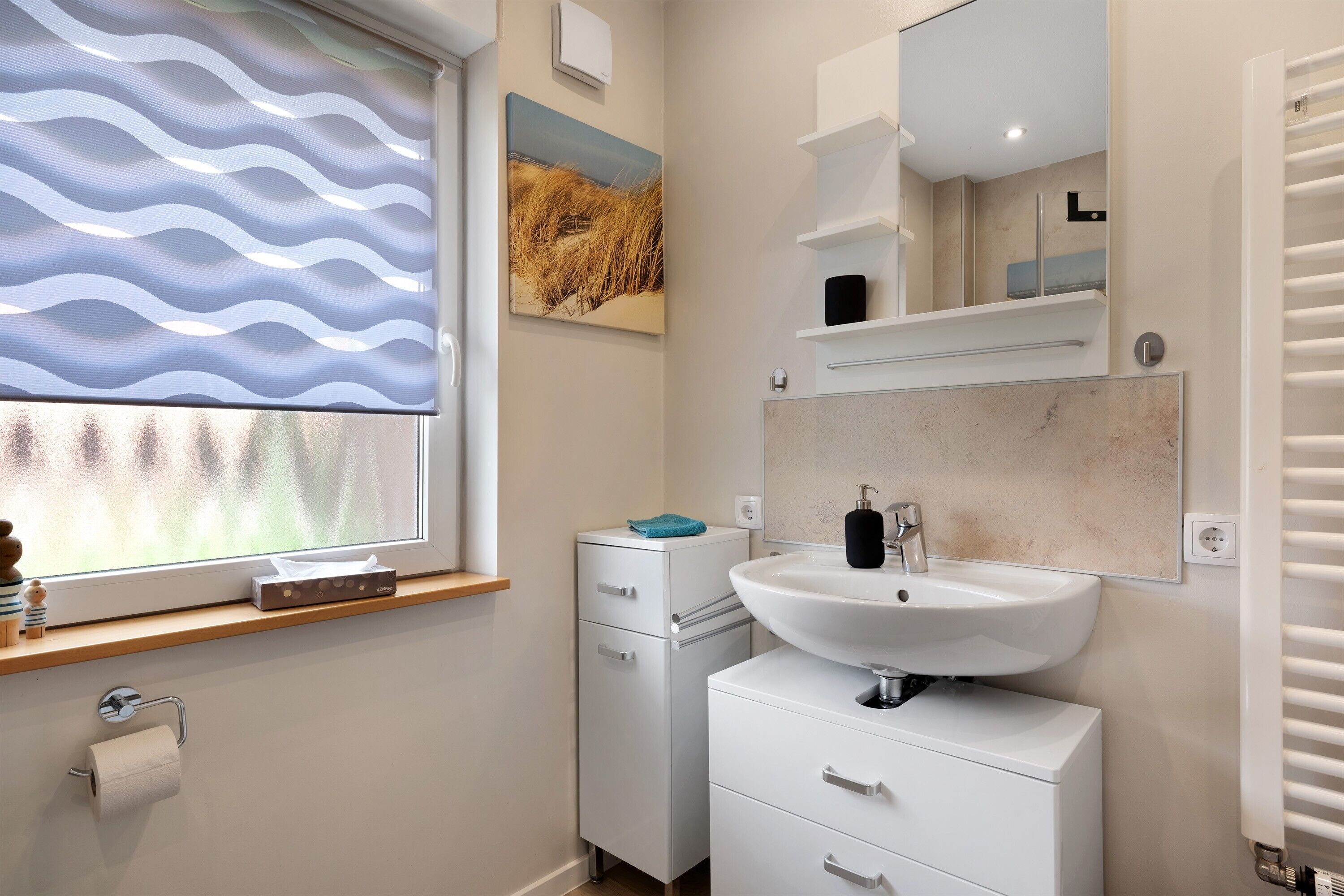 A bathroom with a window, a sink, a mirror, and a towel rack.