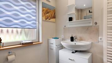 A bathroom with a window, a sink, a mirror, and a towel rack.