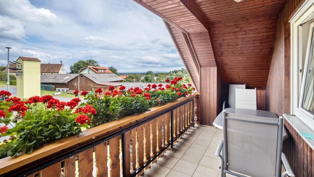 A balcony with a wooden railing, a table, and chairs. - Apartment 'Ferienwohnung Bächer' with Shared Garden, Balcony and Wi-Fi (Wiesau)