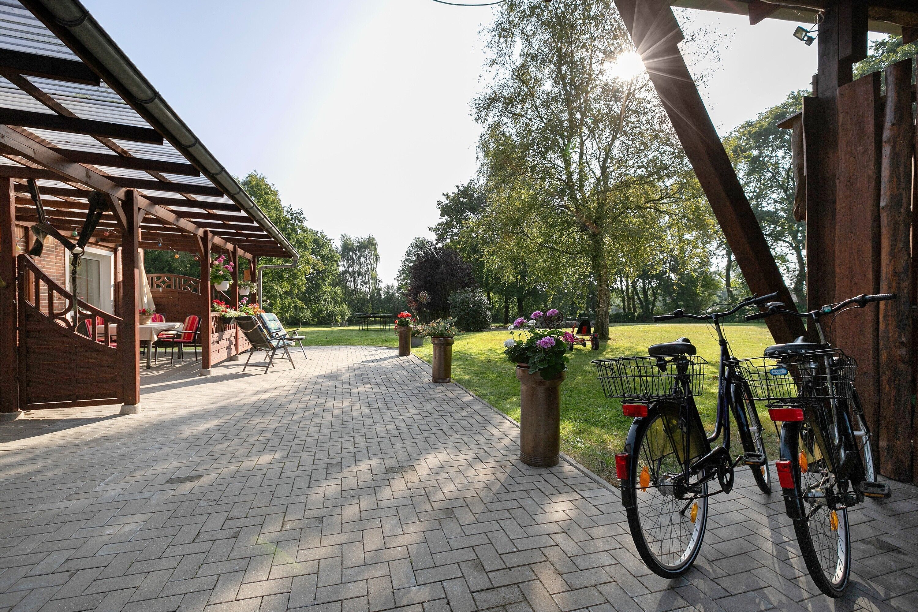 Eine überdachte Terrasse mit Ziegelboden, Sitzgelegenheiten im Freien und Fahrrädern.