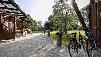 Eine überdachte Terrasse mit Ziegelboden, Sitzgelegenheiten im Freien und Fahrrädern.