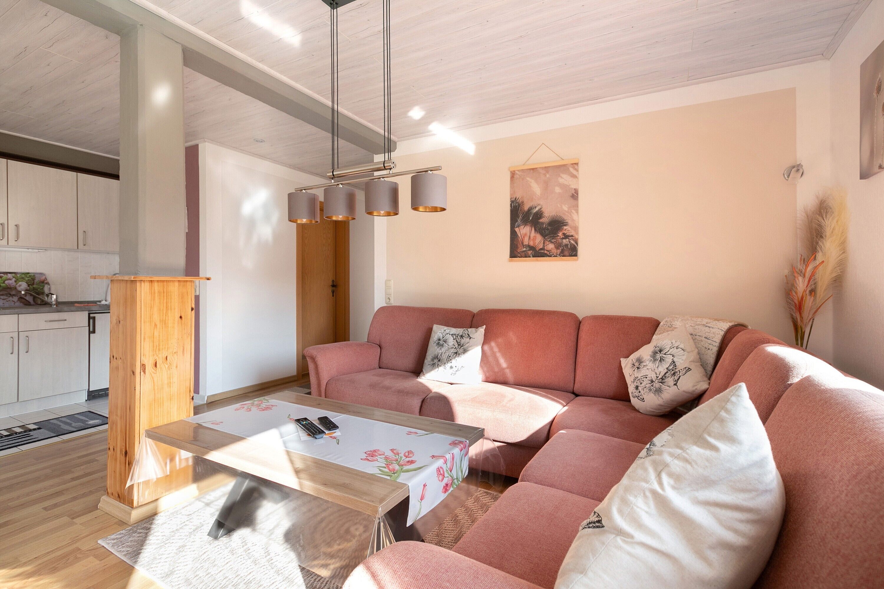 A modern living room with a sofa, a coffee table, and a hanging light fixture.