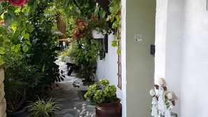 A narrow stone pathway leading to a white building with a 'Willkommen' sign, surrounded by lush greenery and potted plants. - Apartment 'Ferienwohnung 3' with Mountain View, Shared Garden and Wi-Fi (Grassau)
