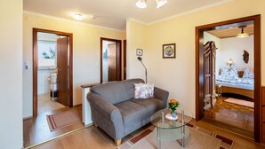 A living room with a sofa, a glass coffee table, a door leading to another room, and a ceiling light fixture. - Apartment 'Ferienwohnung 3' with Mountain View, Shared Garden and Wi-Fi (Grassau)
