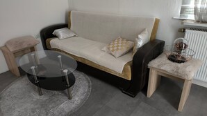 A modern living room with a sofa, a glass coffee table, a side table, and a radiator. - Apartment in Krumbach with Shared Terrace (Krumbach (Schwaben))