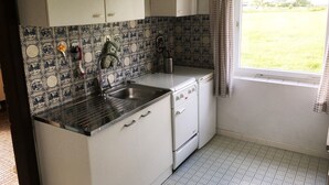 Una cocina compacta con lavabo, estufa y armarios blancos.