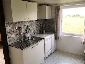 A compact kitchen with a sink, stove, and white cabinets.
