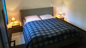 Un dormitorio con una cama, dos mesitas de noche y dos lámparas.