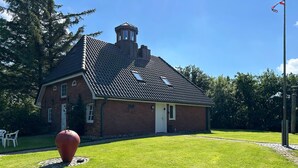 A brick building with a sloped roof, a small tower, and a flagpole.