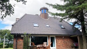 A brick house with a tiled roof, a chimney, and a patio with outdoor furniture.