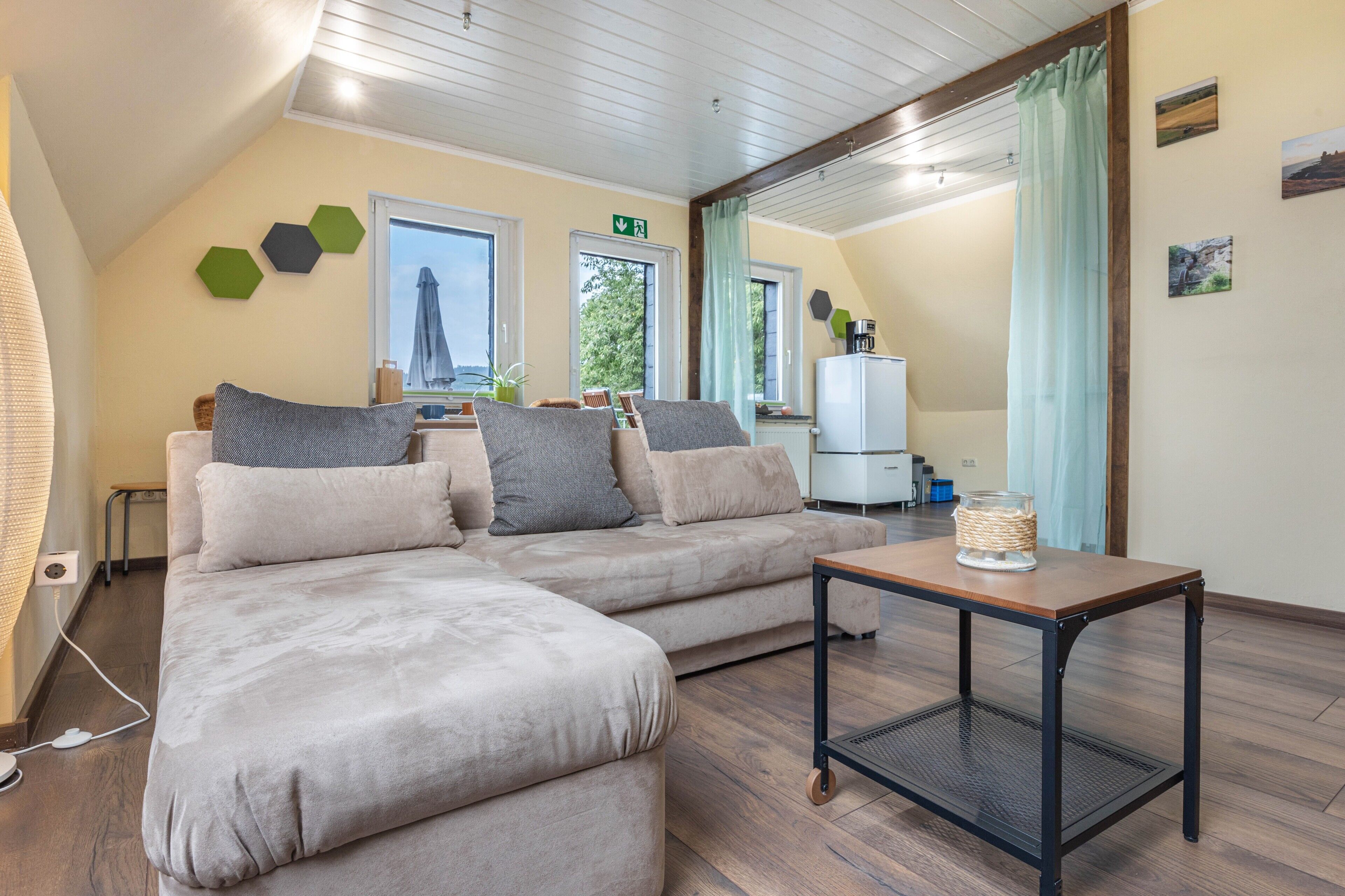 Ein modernes Wohnzimmer mit einer Eckcouch, einem Couchtisch und Blick ins Freie.