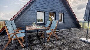 Un bâtiment triangulaire avec un toit en pente, une table entourée de chaises et une petite fenêtre.