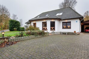 A house with a paved driveway, a lawn, and a garage. - Apartment 'Offenbüttel' with Private Terrace, Shared Garden and Wi-Fi (Offenbüttel)