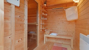 A wooden sauna room with a bench, shelves, a plant, and a sauna control panel. - Apartment 'Offenbüttel' with Private Terrace, Shared Garden and Wi-Fi (Offenbüttel)