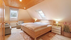 A bedroom with a sloped ceiling, a bed, a chair, a nightstand, and a window. - Apartment 'Offenbüttel' with Private Terrace, Shared Garden and Wi-Fi (Offenbüttel)