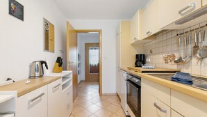 A kitchen with white cabinets, a wooden countertop, and a tiled backsplash. - Holiday Apartment Auszeit an der Eider – Relax in Idyllic Hennstedt (Hennstedt)