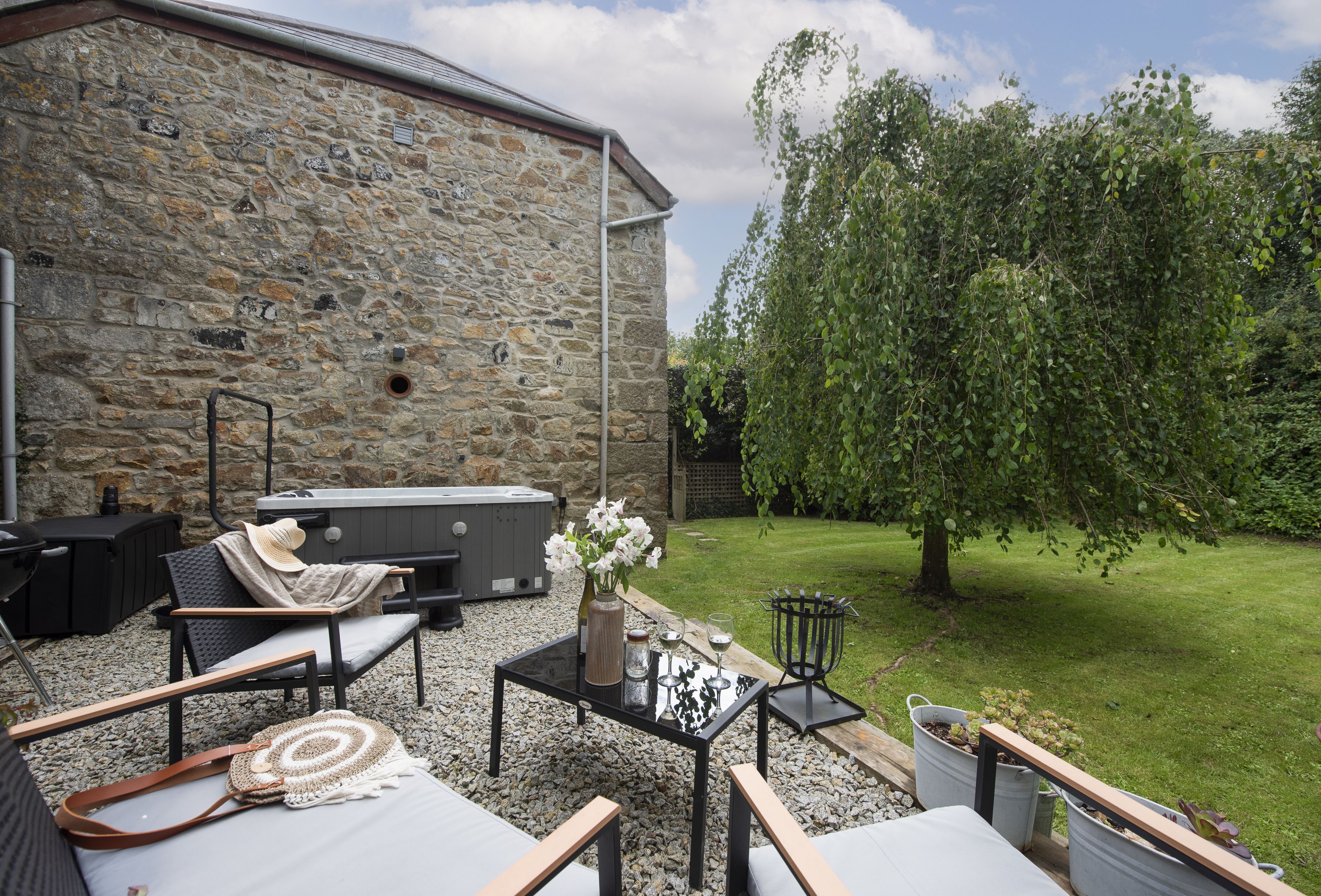 A stone building with outdoor seating, a hot tub, and a garden.