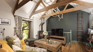 A cozy living room with a wooden ceiling, a sofa, a coffee table, and a fireplace. - Quaint and cosy, this reverse layout barn conversion exudes original charm and ultimate luxury. Quin (Camborne)