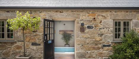 A stone building with a door leading to a pool area.