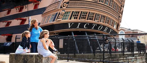A curved building with the word 'VICTORY' on its facade, a stone bench, and a metal fence in the foreground.