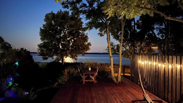 Een houten terras met een bankje en tafel, met uitzicht op een wateroppervlak.
