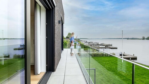 A modern building with a glass facade overlooking a body of water. - Attractive villa with jetty (Kamperland)