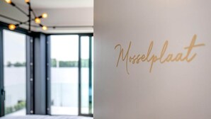 A room with a large window, a bed, and a wall with the text "Mosselplaat" in gold. - Attractive villa with jetty (Kamperland)