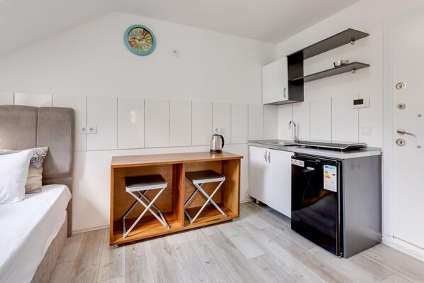 Una kitchenette compacta con lavavajillas integrado, una pequeña encimera y un reloj de pared.