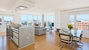 A modern apartment with a kitchen, dining area, and living space, featuring large windows and a city view. - Solaga - Linaje (Málaga)