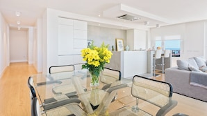 A modern living room with a glass dining table, a sofa, and a view of the sea. - Solaga - Linaje (Málaga)