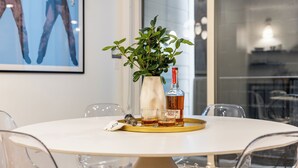 Et rundt bord med en hvid vase, en flaske og glas, omgivet af transparente stole.