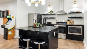 Et moderne køkken med en central ø, barstole, kaffemaskine og en dartskive.