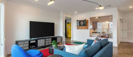 Una sala de estar moderna con un sofá azul, un tapete rojo, un mueble de entretenimiento negro y un televisor de pantalla plana.